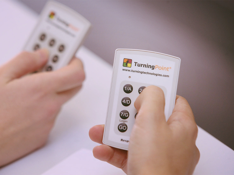 A close up of two hands holding Turning Point clickers