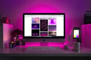 Computer screen and desktop items with purple lighting in the background