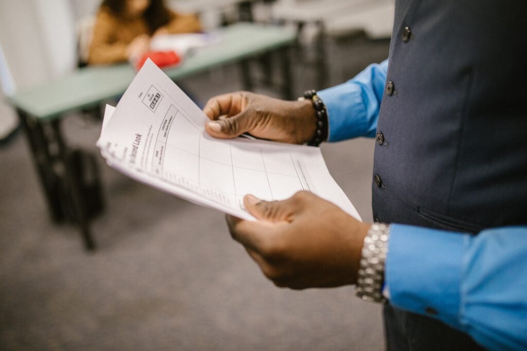 Image of person holding a paper in a classroom